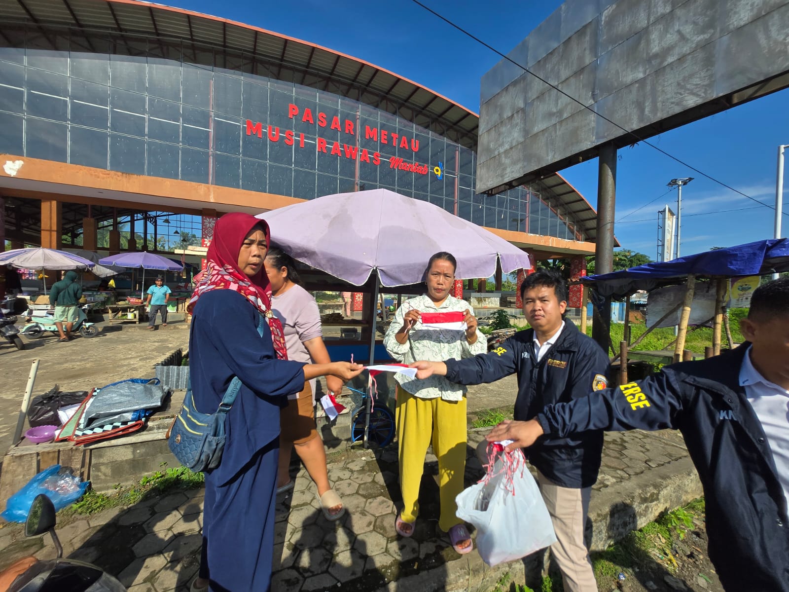 Satreskrim Polres Musi Rawas Bagikan Bendera Merah Putih kepada Masyarakat di Pasar Metau, Muara Beliti